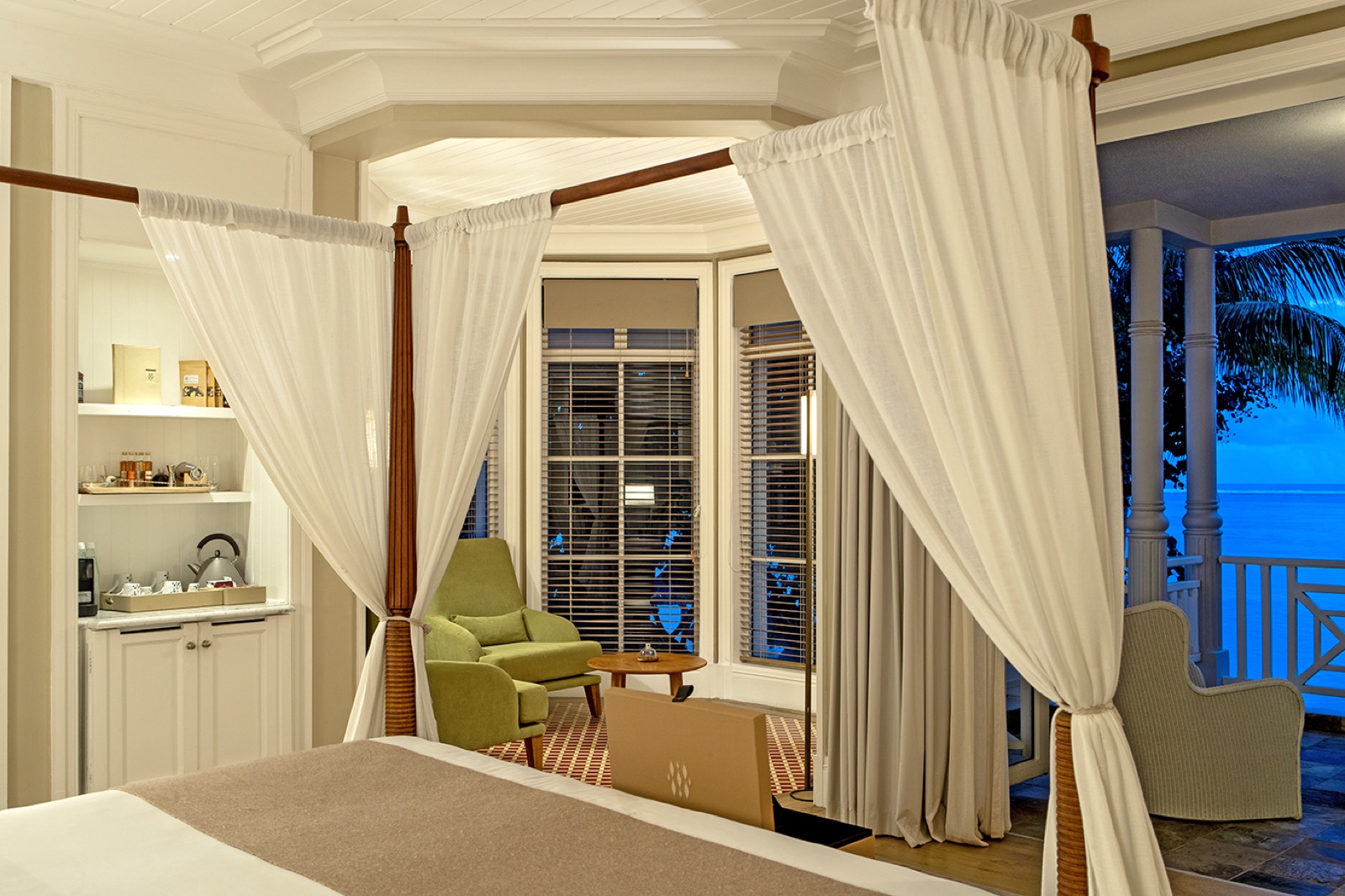 Chambre de suite avec un grand lit à baldaquin drapé de voilages blancs