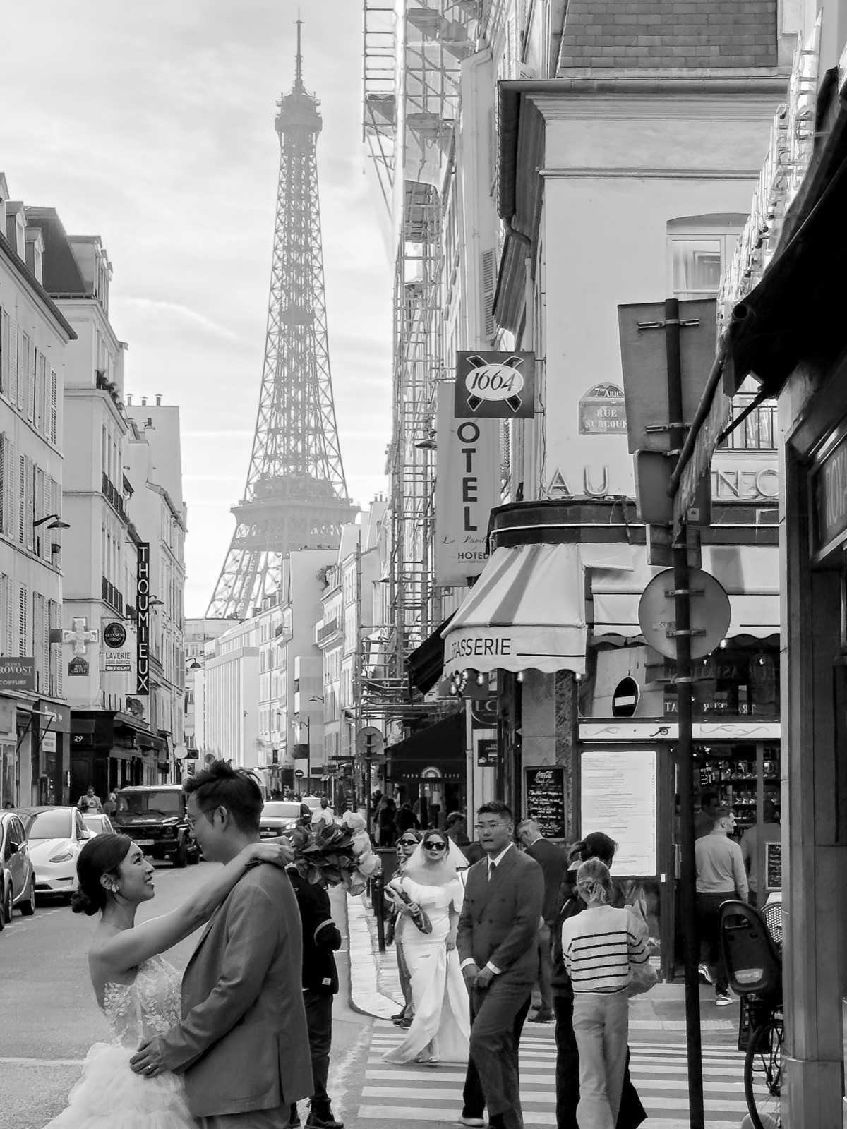 Mariés posant dans une rue parisienne, la tour Eiffel en arrière-plan, photographie en noir et blanc